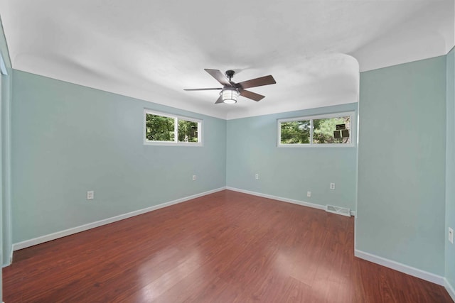 empty room featuring plenty of natural light, ceiling fan, and dark hardwood / wood-style floors