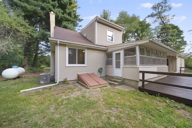 rear view of property with a yard, a sunroom, and a deck