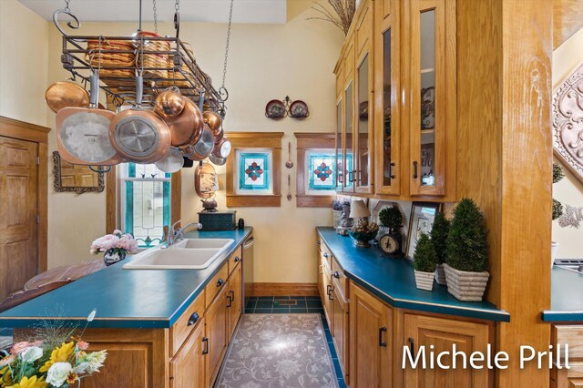 kitchen featuring stainless steel dishwasher, dark tile patterned floors, and sink