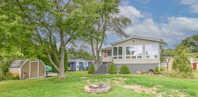 view of front of home with a fire pit, a front yard, and a shed