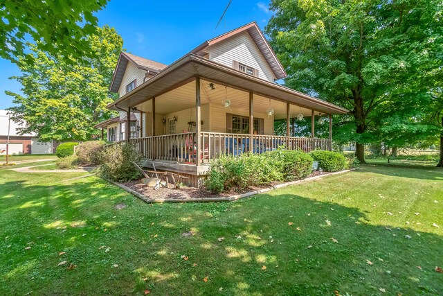 rear view of house featuring a lawn and covered porch