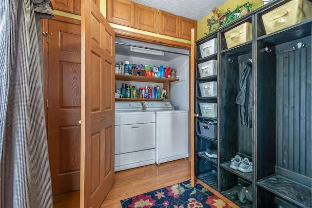 washroom featuring a textured ceiling, washing machine and dryer, and light hardwood / wood-style floors