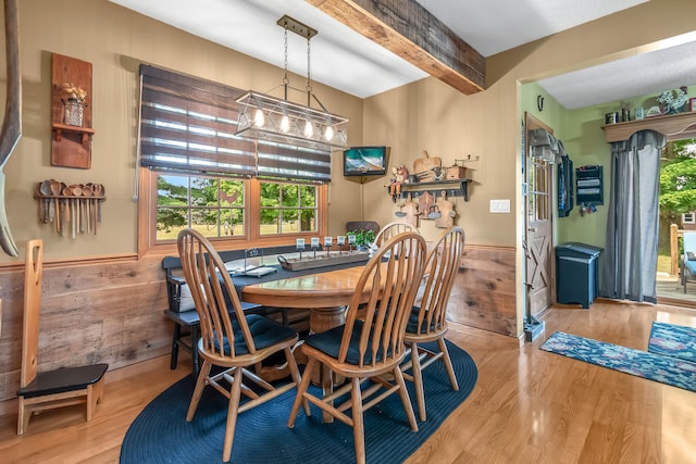 dining space featuring light hardwood / wood-style flooring, wood walls, and beam ceiling