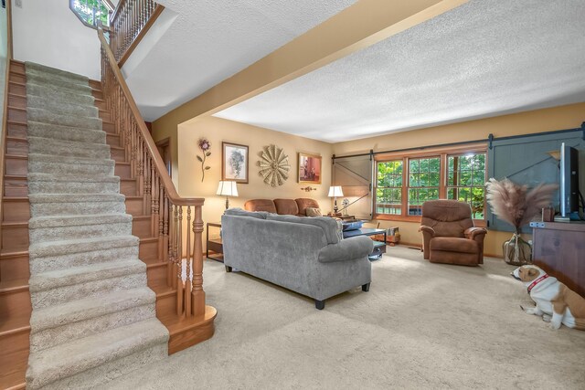 carpeted living room featuring a textured ceiling and a barn door