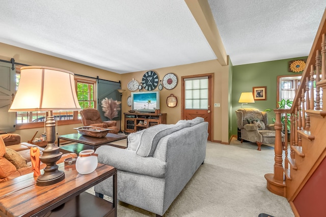 living room with light carpet, beamed ceiling, a barn door, and a textured ceiling