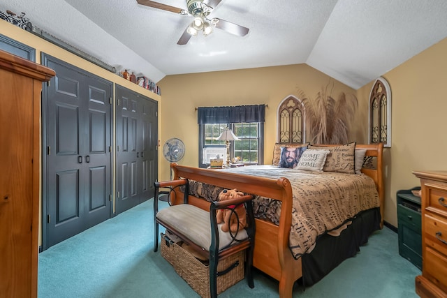 bedroom with lofted ceiling, a closet, carpet floors, ceiling fan, and a textured ceiling