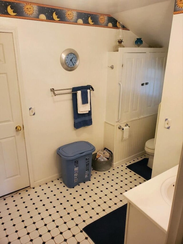 bathroom with lofted ceiling, vanity, and toilet