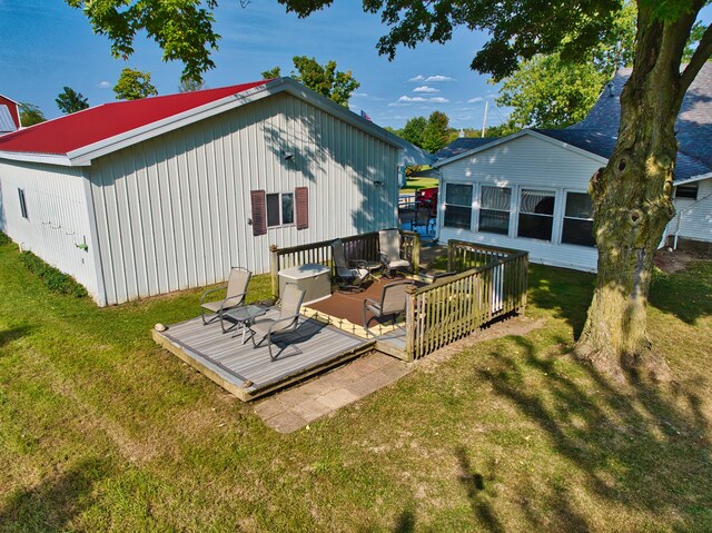 rear view of property with a deck and a lawn