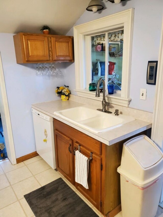 kitchen with light tile patterned floors, white dishwasher, and sink