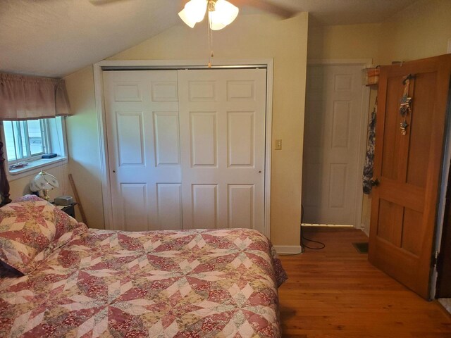 bedroom with hardwood / wood-style floors, ceiling fan, a closet, and vaulted ceiling