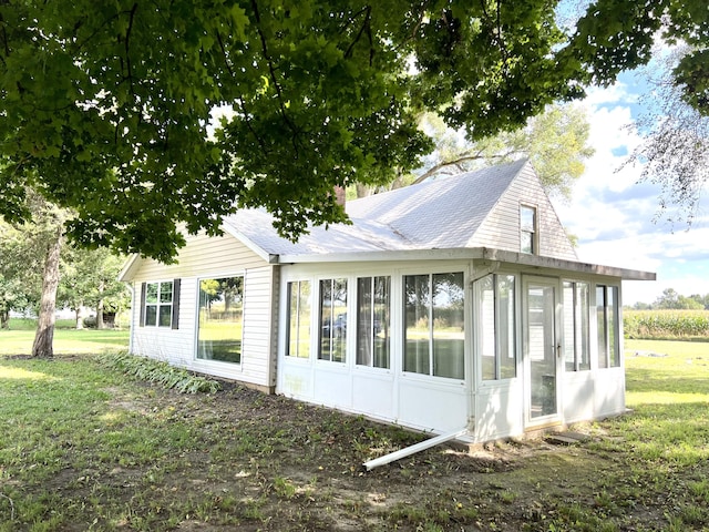 view of home's exterior featuring a yard, a shingled roof, a chimney, and a sunroom