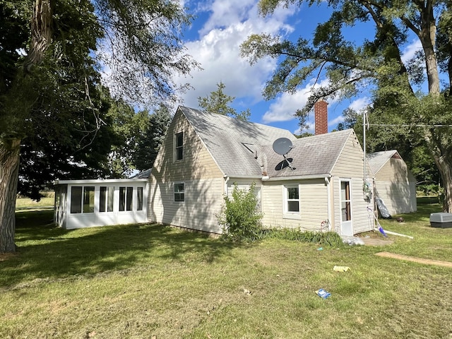 view of side of property with a yard, a chimney, and a sunroom