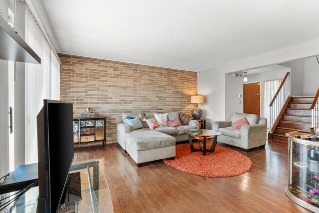 living room with brick wall and dark hardwood / wood-style flooring