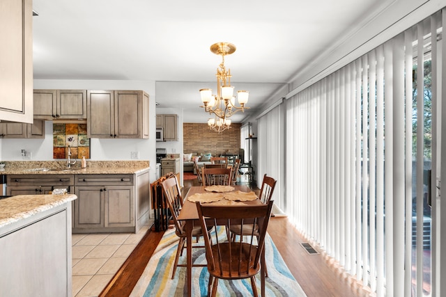 kitchen with hanging light fixtures, light stone counters, a chandelier, and light hardwood / wood-style flooring