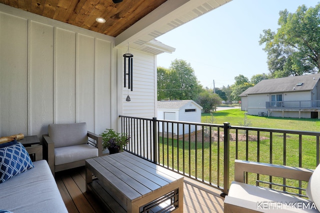 wooden terrace featuring a lawn, an outbuilding, and outdoor lounge area