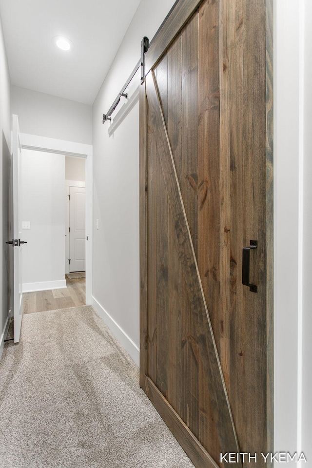 hallway featuring a barn door and light hardwood / wood-style flooring