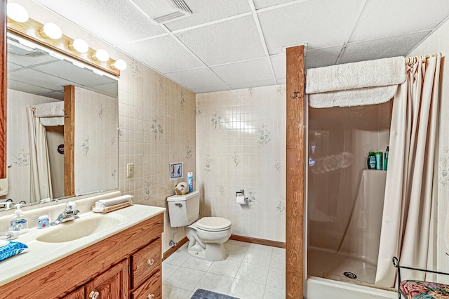 bathroom with a drop ceiling, tile patterned floors, curtained shower, and toilet