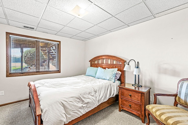 bedroom featuring a drop ceiling and light colored carpet