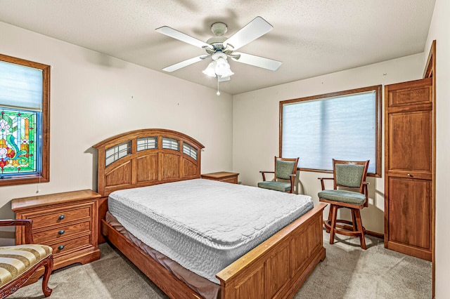 bedroom with ceiling fan, a textured ceiling, and light carpet