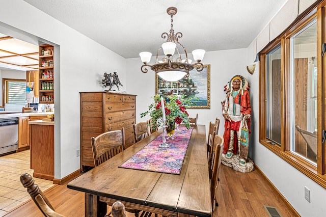 dining space featuring light hardwood / wood-style flooring, a chandelier, and a textured ceiling