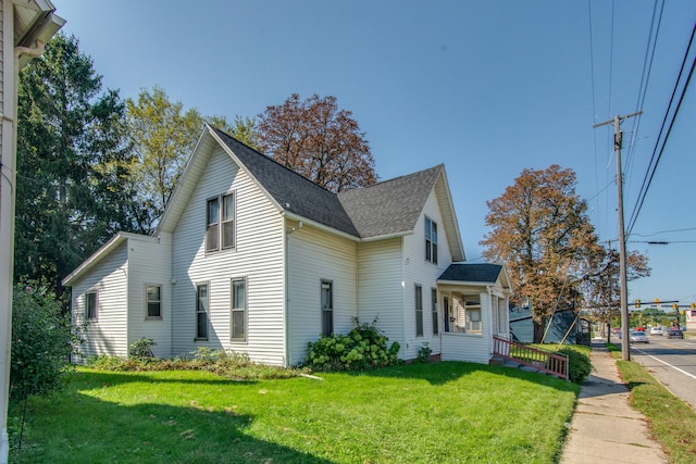 view of home's exterior with a lawn and roof with shingles