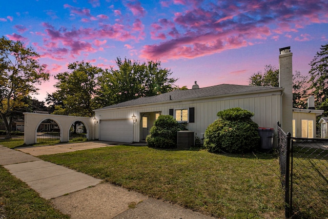 view of front facade featuring a yard, a garage, and central air condition unit