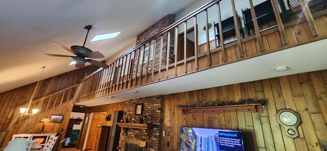 interior space featuring a skylight, high vaulted ceiling, ceiling fan, and wooden walls