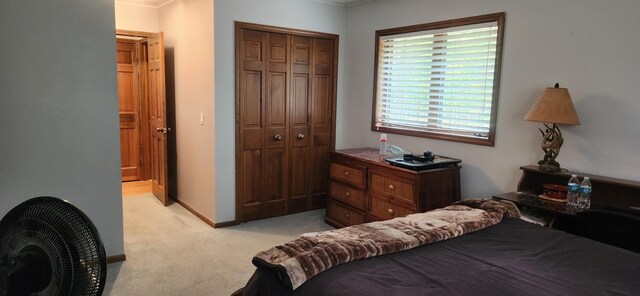 bedroom featuring a closet, light carpet, and baseboards