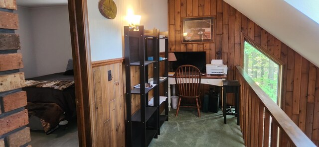 carpeted home office with wood walls and vaulted ceiling