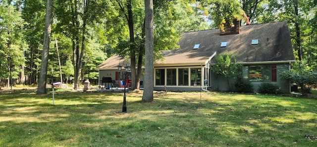 back of house featuring a lawn and a chimney
