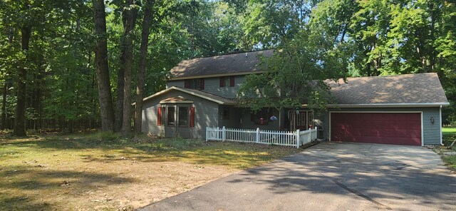 view of front of house featuring driveway, a shingled roof, an attached garage, and fence