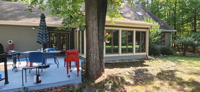 back of property with a deck, french doors, and roof with shingles