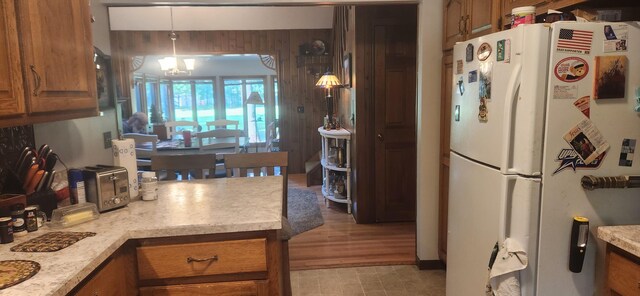 kitchen with freestanding refrigerator, hanging light fixtures, light countertops, brown cabinets, and a chandelier