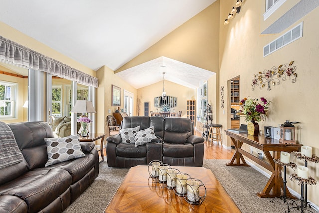 living room featuring high vaulted ceiling, a chandelier, and wood-type flooring