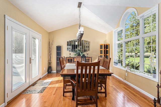 dining area featuring light wood-type flooring, french doors, a wealth of natural light, and vaulted ceiling