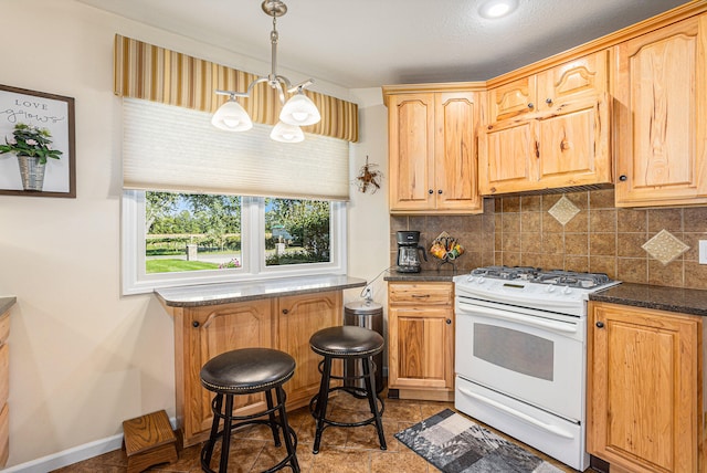 kitchen featuring white range oven, hanging light fixtures, dark stone countertops, a notable chandelier, and tasteful backsplash