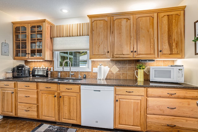 kitchen with a textured ceiling, dark stone countertops, sink, and white appliances