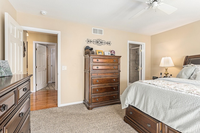 bedroom with light colored carpet, ensuite bathroom, and ceiling fan