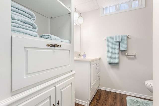 bathroom featuring vanity, toilet, hardwood / wood-style flooring, and a drop ceiling