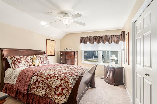 bedroom with vaulted ceiling, light colored carpet, ceiling fan, and a closet