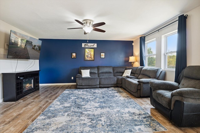 living room featuring a fireplace, wood-type flooring, and ceiling fan