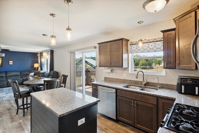 kitchen featuring dishwasher, a center island, sink, light wood-type flooring, and a wealth of natural light