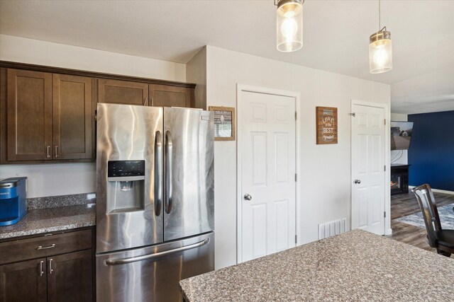 kitchen featuring light stone countertops, stainless steel refrigerator with ice dispenser, dark hardwood / wood-style floors, and dark brown cabinets