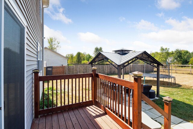 wooden deck featuring a gazebo, a yard, and a trampoline