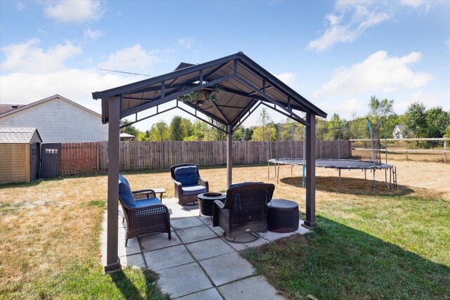 view of yard with an outdoor living space with a fire pit, a gazebo, a patio, a trampoline, and a storage unit