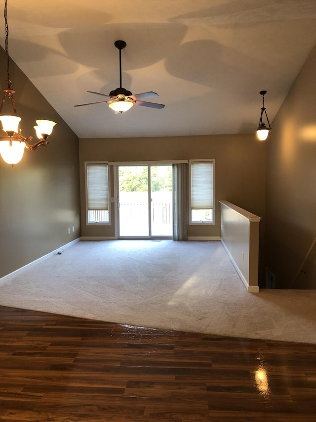 unfurnished room with lofted ceiling, ceiling fan with notable chandelier, and dark wood-type flooring