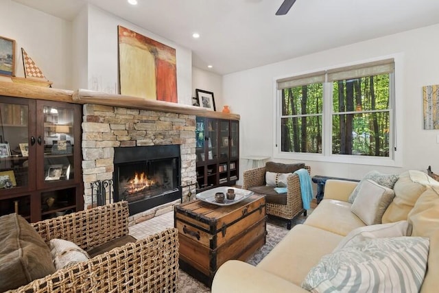 living room featuring ceiling fan and a stone fireplace