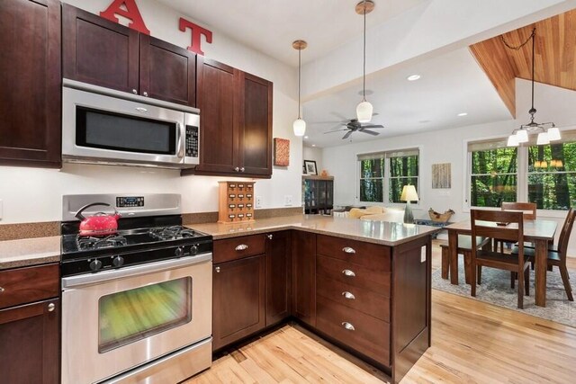 kitchen with kitchen peninsula, light wood-type flooring, stainless steel appliances, ceiling fan, and decorative light fixtures