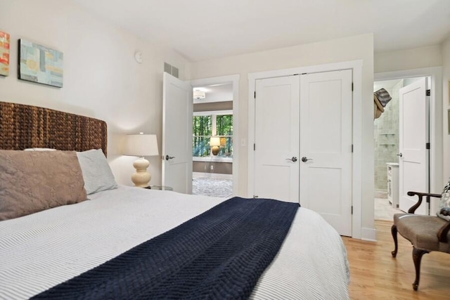 bedroom featuring connected bathroom, light hardwood / wood-style flooring, and a closet