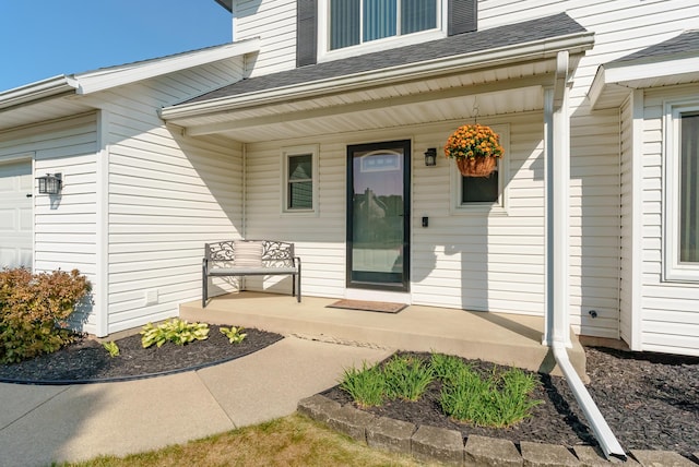 view of exterior entry featuring covered porch and a garage